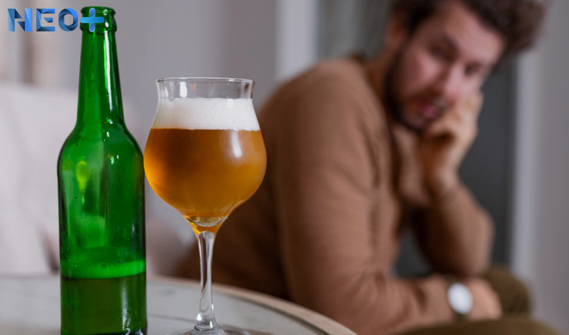бутылка и стакан с пивом на фоне грустного мужчины